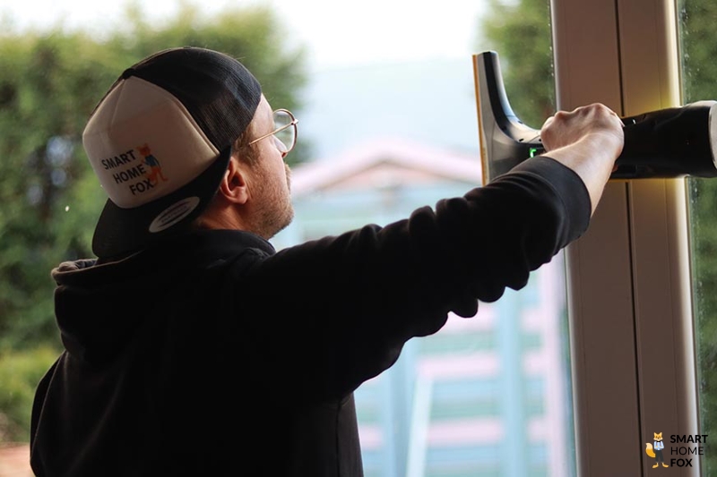 Man sieht einen Mann, der einen Fenstersauger nutzt.